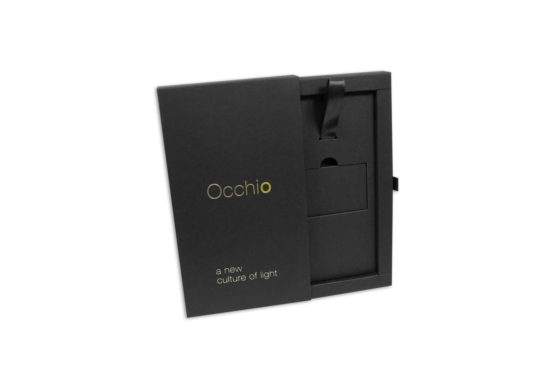 Schwarze Schiebeschachtel mit einem goldenen Logodruck von Occhio. Unten auf der Schachtel ist noch ein kleinerer weißer Druck und die Schachtel ist halb geöffnet. Im Inneren befindet sich ein Inlay, das mit einer schwarzen Schlaufe versehen ist. 